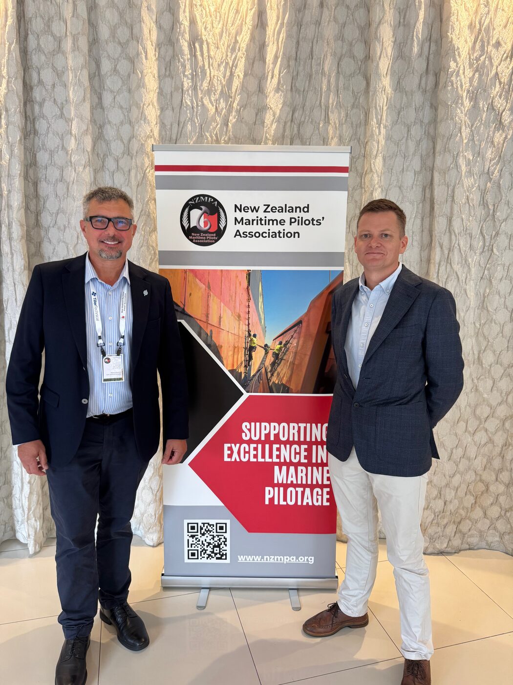 Marco Blanco with Captain Ricky Rouse beside the New Zealand Maritime Pilots&rsquo; Association banner at the 2026 conference in Tauranga